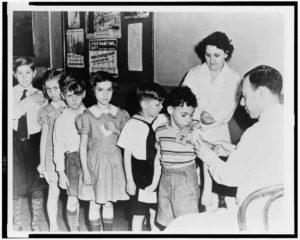 Historical black-and-white photograph of children getting immunized for smallpox.