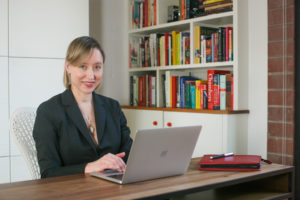 Elisabeth Eaves at her desk with a laptop. There is a bookshelf behind her.